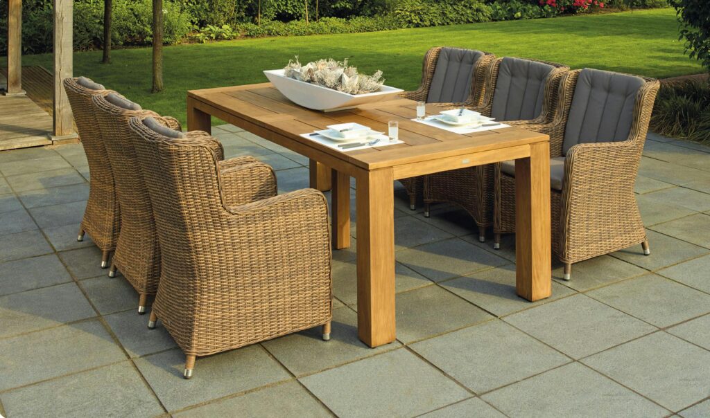 A serene outdoor patio set up with rattan chairs and a wooden table, perfect for relaxation.